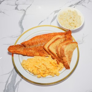 Hearty breakfast plate at Destinis — fried fish, eggs, and toast